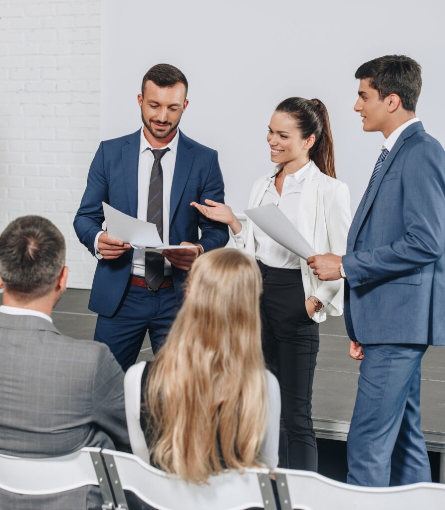smiling businesspeople talking about documents during training in hub